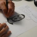 Eine Gamedesignerin zeichnet eine Illustration von einem Spielcharakter auf einem Blatt Papier.
