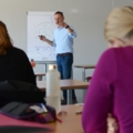 Das Bild zeigt eine Unterrichtsszene an einer Fachhochschule, in der ein Dozent im Studiengang Gesundheits- und Pflegemanagement unterrichtet.