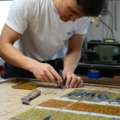 Ein Glasbautechniker arbeitet konzentriert an einem Buntglasprojekt.
