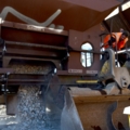 Ein Gleisbautechniker in Warnweste bedient eine Baumaschine, die Schotter von einem Güterwaggon aufnimmt.