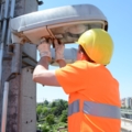 Ein Gleisbautechniker in Sicherheitskleidung repariert eine Straßenlaterne.