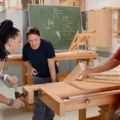 Auf dem Bild sind ZimmerInnen in einer Werkstatt zu sehen, die sich mit Holzarbeiten beschäftigen.