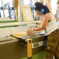 Eine Zimmerin arbeitet an einer Holzbearbeitungsmaschine in einer Werkstatt.