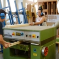 Zwei Zimmerinnen arbeiten in einer Tischlerei und bedienen eine Hobelmaschine.
