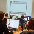 In dem Bild sieht man angehende Immobilienkaufleute, die an Computern arbeiten und einem Vortrag zuhören.