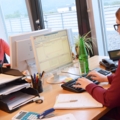 Auf dem Bild arbeiten zwei Immobilienkaufleute an Schreibtischen mit Computern.
