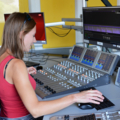 Eine Journalistin bedient ein Mischpult in einem Tonstudio.