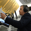 Ein Moderator steht in einem Tonstudio und spricht in ein Mikrofon.