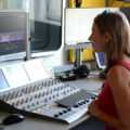 Eine Journalistin arbeitet an einem Mischpult in einem Radiostudio.