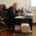 Ein Investigativer Journalist arbeitet an einem Schreibtisch mit einem Laptop in einem Büro.