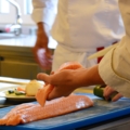 Auf dem Bild ist ein Koch zu sehen, der frischen Lachs filetiert.