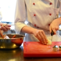 Zwei Köchinnen in Arbeitskleidung bereiten in einer Küche Gemüse zu.