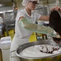 Eine Konditorin mischt Schokoladenmasse in eine große Schüssel mit einer weißen Creme.
