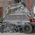 Das Bild zeigt einen Bagger auf einer Baustelle, der Erdarbeiten durchführt.
