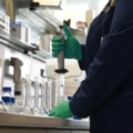 Das Bild zeigt eine Labortechnikerin, die in einem Labor mit Chemikalien arbeitet und dabei ein Pipettiergerät benutzt.