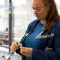 Auf dem Bild ist eine Person zu sehen, die in einem Labor arbeitet und mit Glasgefäßen hantiert, was typisch für den Beruf einer Labortechnikerin oder eines Labortechnikers im Bereich Chemie oder Biotechnologie ist.