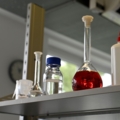 Das Bild zeigt Laborutensilien wie Reagenzgläser, Flaschen und Chemikalien, die typisch für den Beruf eines Labortechnikers sind.
