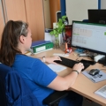 Auf dem Bild ist eine Labortechnikerin zu sehen, die am Computer arbeitet.