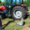 Ein Land- und Baumaschinentechniker führt mit einem Laptop und Diagnosegeräten Wartungsarbeiten an einem Traktor durch.