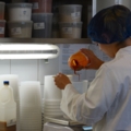 Eine Lebensmitteltechnikerin in Schutzkleidung wiegt und mischt Zutaten in einem Labor ab.