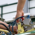 Das Bild zeigt Hände eines Luftfahrzeugtechnikers, die an einer komplexen mechanischen Vorrichtung an einem Teil eines Flugzeugs arbeiten.