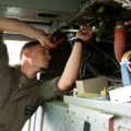 Auf dem Bild ist ein Luftfahrzeugtechniker zu sehen, der in einem Flugzeug arbeitet und technische Wartungsarbeiten durchführt.