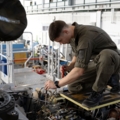 Auf dem Bild ist ein Luftfahrzeugtechniker zu sehen, der an einem Flugzeugmotor arbeitet.