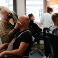 In dem Bild schminkt eine Visagistin einen Schauspieler.