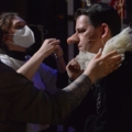 Ein Schauspieler wird von einer Maskenbildnerin für eine Theaterproduktion vorbereitet.