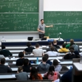 Ein Dozent hält einen Mathematikvortrag vor Studierenden in einem Hörsaal.