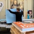 Ein Medienfachmann arbeitet in einer Druckerei und platziert große Druckbögen auf einer Maschine.