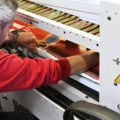 Ein Medienfachmann arbeitet an einer Druckmaschine und überprüft gedruckte Materialien.