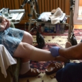 Ein Pflegeassistent kümmert sich um die Beine einer älteren Person.