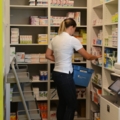 Eine pharmazeutisch-kaufmännische Assistentin sortiert Medikamente in einem Apothekenlager.