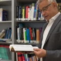 Ein Psychologe steht in einer Bibliothek und liest ein Fachbuch.