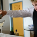Ein Restaurantfachmann gießt einen Cocktail durch einen Barsieb in ein Glas.