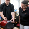 Zwei ServicetechnikerInnen reparieren einen Staubsauger.