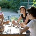 Auf dem Bild ist eine Sozialarbeiterin zu sehen, die mit KlientInnen an einem Tisch Karten spielt.