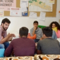 Ein Sozialarbeiter sitzt mit einer Gruppe von SchülerInnen in einer gemütlichen Lernumgebung und diskutiert.
