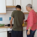 Eine Sozialpädagogin hilft einem Klienten in einer sozialpädagogischen Einrichtung in der Küche.