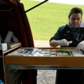 Auf dem Bild ist eine Tierärztin zu sehen, die eine mobile Tierarztpraxis in einem Fahrzeug organisiert, mit Medikamenten und medizinischem Zubehör.