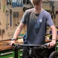 Ein junger Mann arbeitet in einer Fahrradwerkstatt und repariert ein Fahrrad.