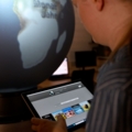 Eine Person bedient ein Tablet vor einem beleuchteten Globus in einem wissenschaftlichen Umfeld.
