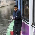 Eine Person arbeitet auf einem Boot und hält ein Seil.