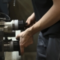 Das Bild zeigt eine Person, die an einer Werkzeugmaschine arbeitet.